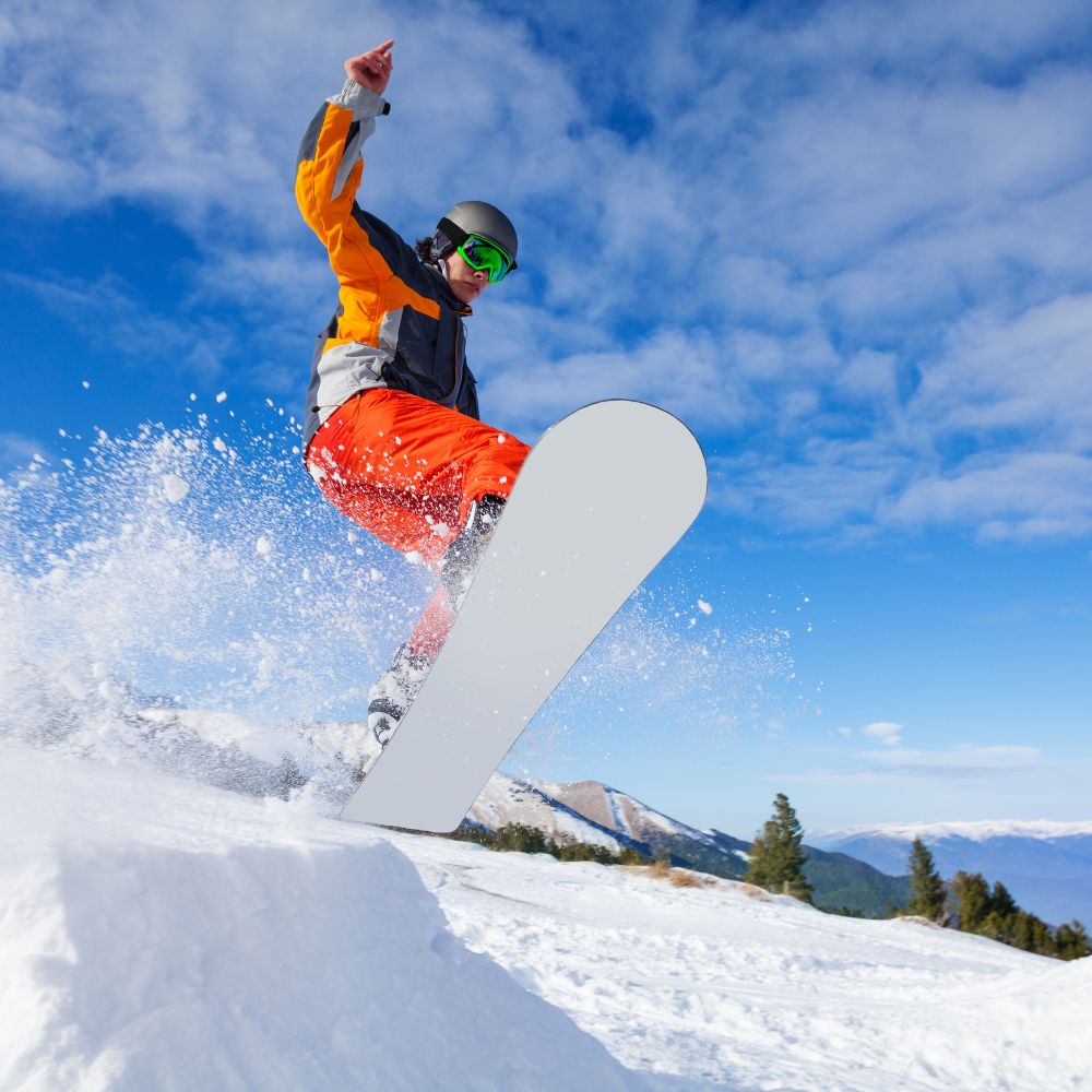 Person snowboarding in the air with a blue sky and mountains in the background